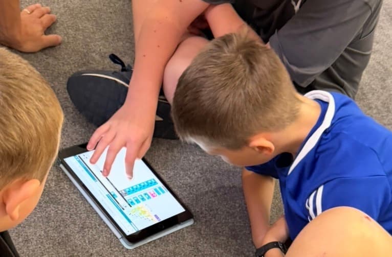 Pupils working together on an iPad creative app during a workshop